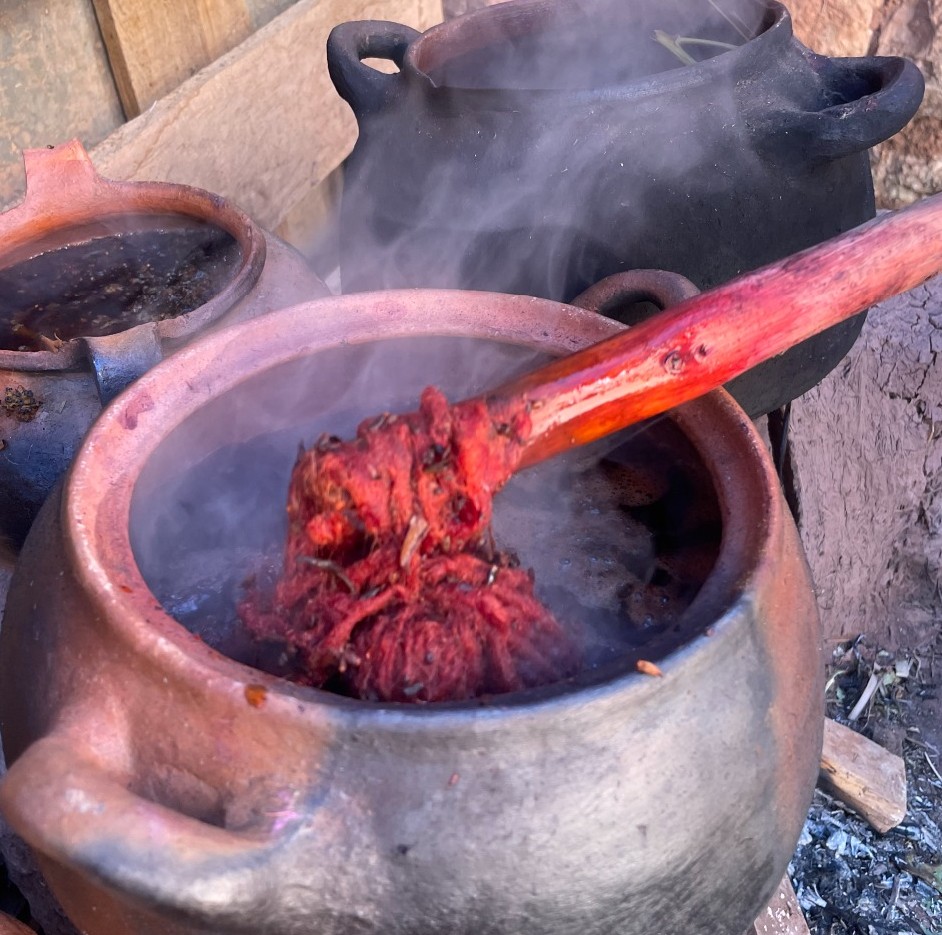 Wool being dyed red in a steaming clay pot