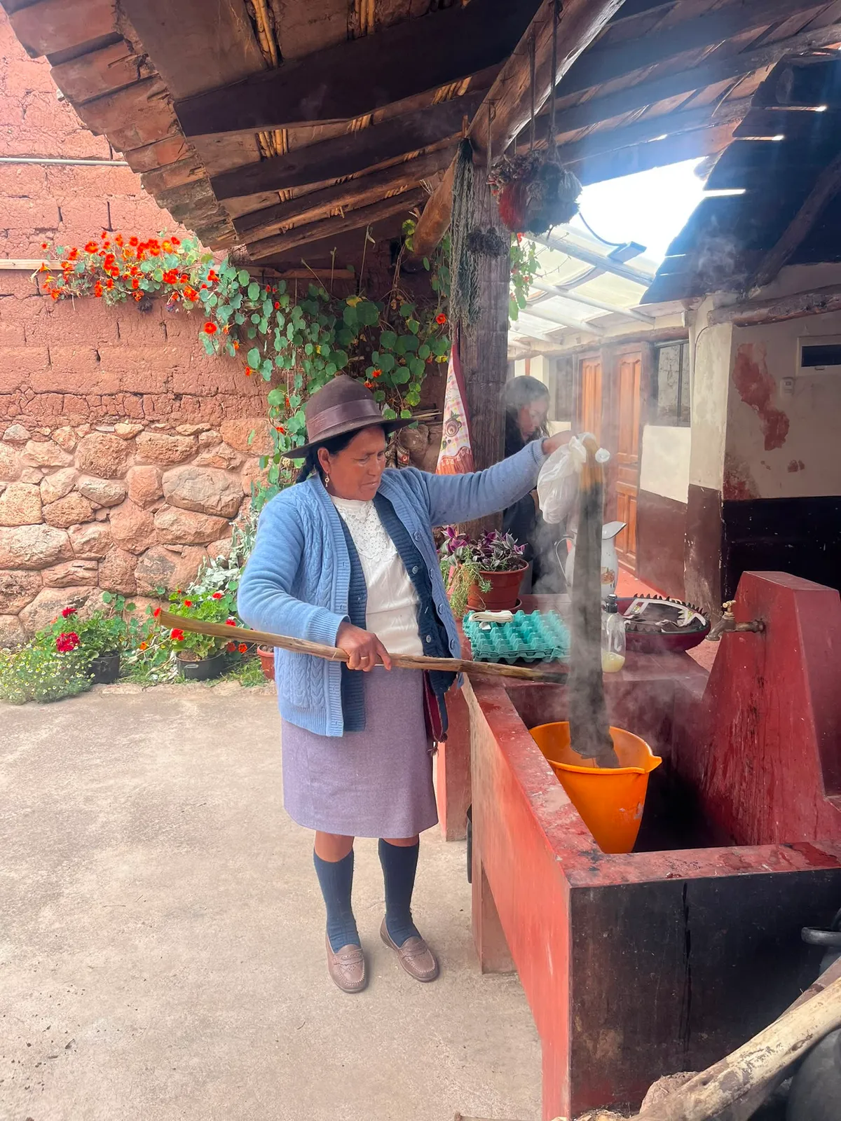 Artisan in a hat lifting dyed wool from a steaming pot